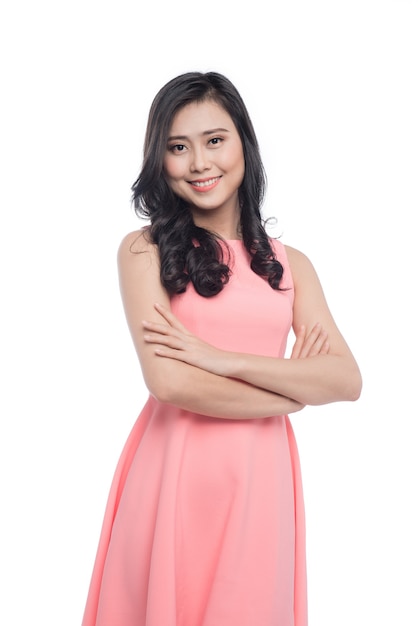 Asian young beautiful woman with long black hair in pink dress standing over white.