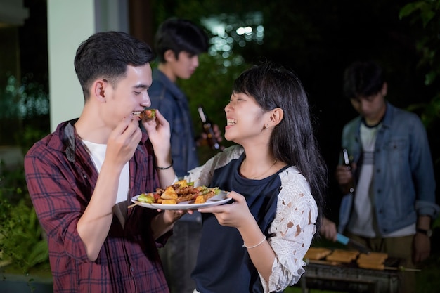 낭만적 인 저녁 식사와 야외 정원 바베큐 l을 갖는 친구의 그룹을 즐기는 아시아 젊은 부부