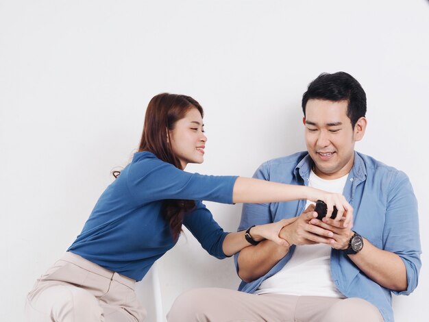 Asian young couple lover fighting for a smart phone in living room at home.