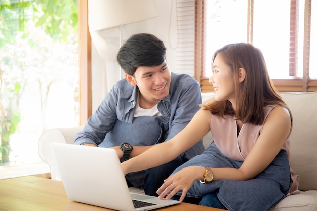 Asian young couple using laptop computer think and searching internet together