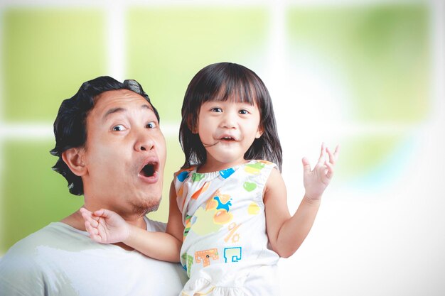 Asian young dad and his daughter have fun while being carried in his father's arms happy family