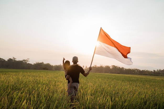 Asian young father with doughter flapping Indonesian flag