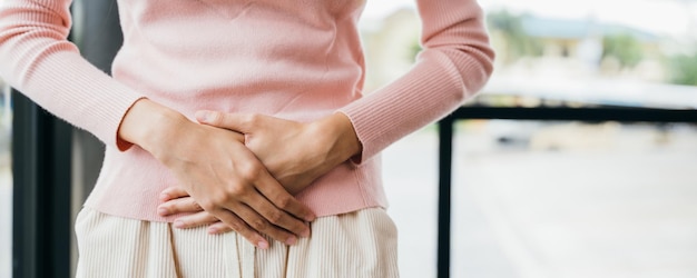 Asian young female unhappy unwell sick ill hand holding on stomach suffers pain at home