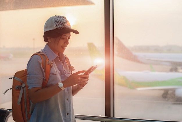 Foto ragazza asiatica check flight e check-in volo utilizzando internet nel telefono.