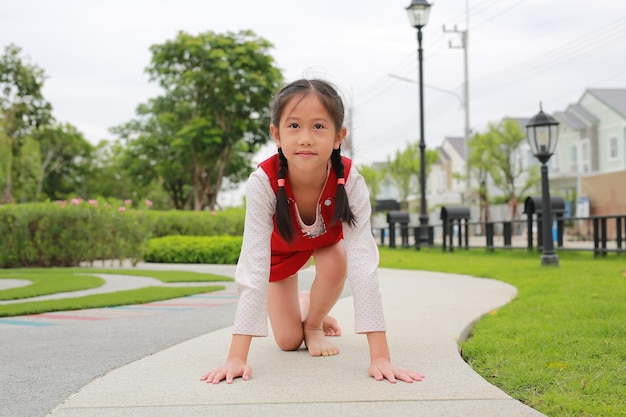 庭で走る準備をしているアジアの若い女の子の子供子供は開始の準備をします