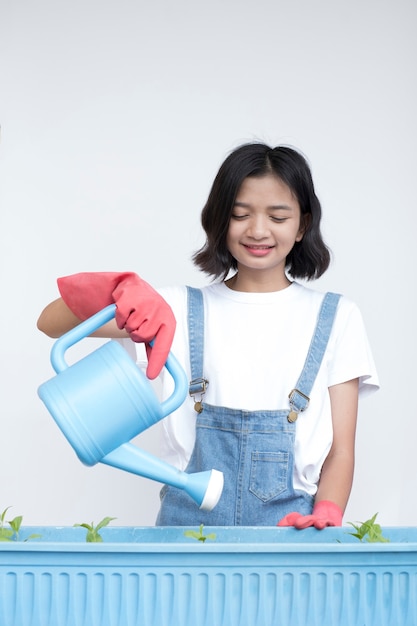 Asian young girl plant a flower wear jean and white shirt with smiling face