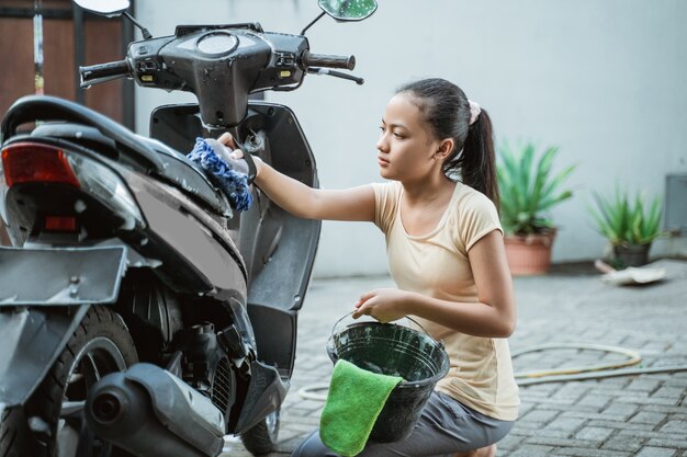 Asian young girl washing a motorcycle