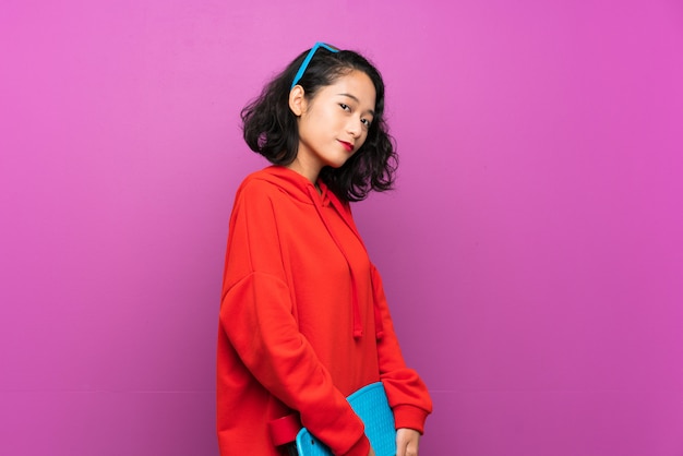 Asian young girl with skate over purple background