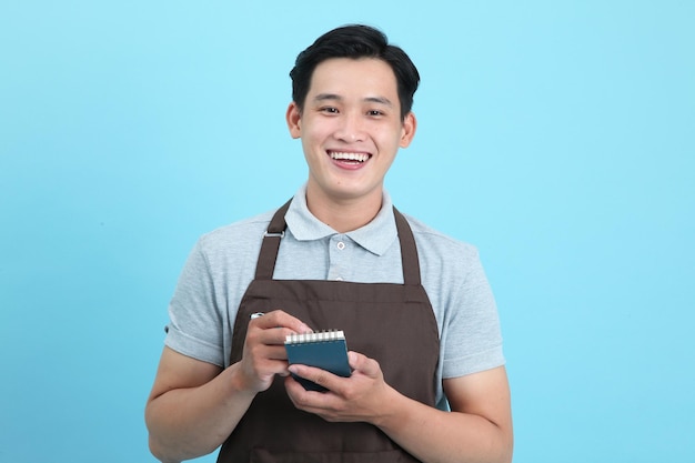 Asian young handsome man in waiter uniform welcome guest and take order