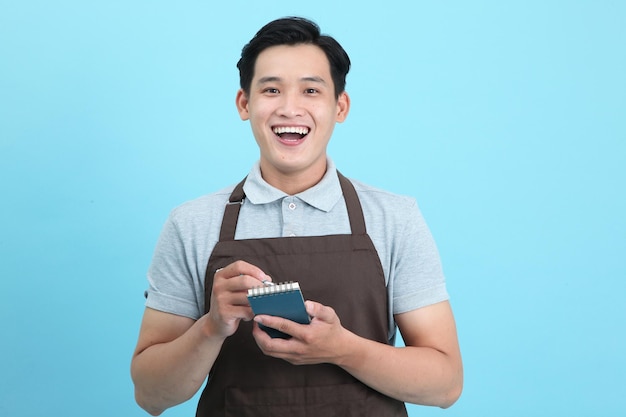 Asian young handsome man in waiter uniform welcome guest and take order