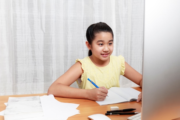 Asian young little girl using pencil to do homework by herself