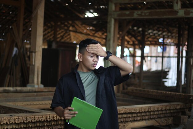 Asian young man boss of wood company confused checking\
quality