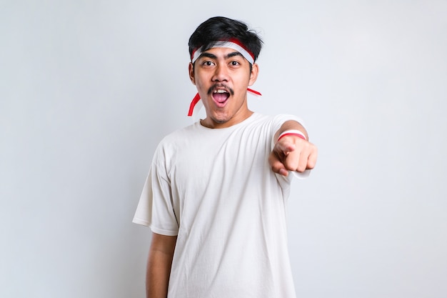 Asian young man in casual shirt pointing forward, Looking at Camera, make choosing you gesture against white background