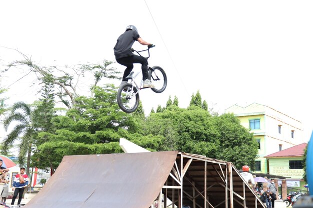 Азиатский молодой человек демонстрирует некоторые трюки фристайла BMX в воздухе.