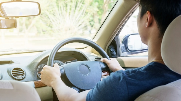 アジアの若い男が車を運転します。