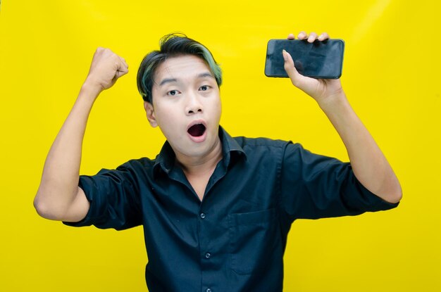 Asian young man gives thumbs up and shouts happily to celebrate his graduation