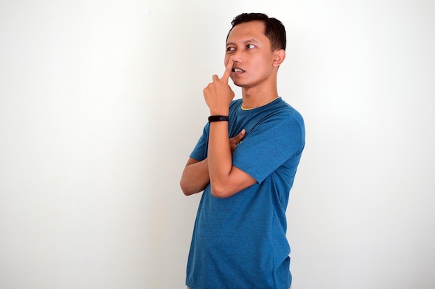 Asian young man is picking his nose isolated on white background