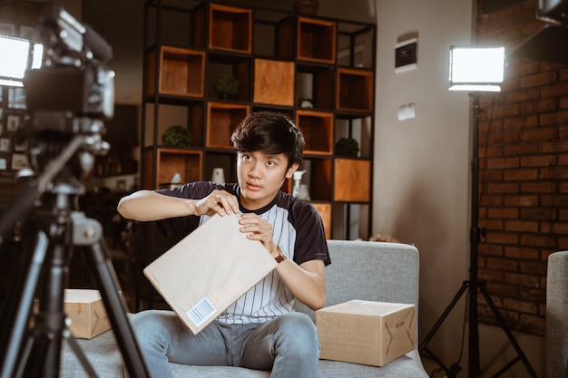 Giovane asiatico che fa video unboxing di registrazione video per vlog