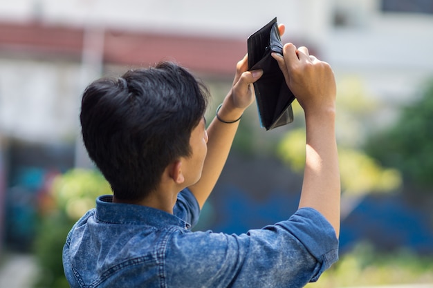 Asian young man  picked up an empty wallet,Asian young man  have no money