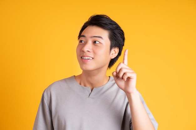 Asian young man posing on a yellow background