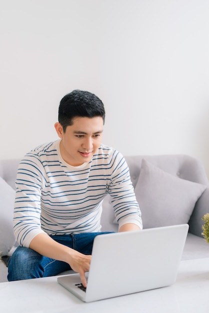 Asian young man relaxing on the sofa with a laptop