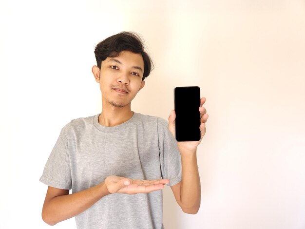 빈 화면으로 스마트폰을 보여주는 아시아 청년