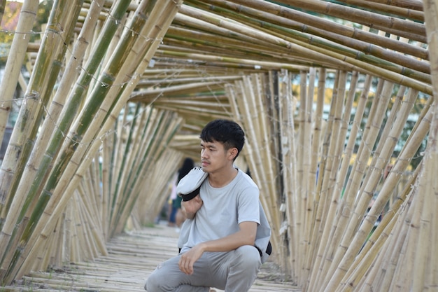Asian young man sitting in a bamboo arch.
