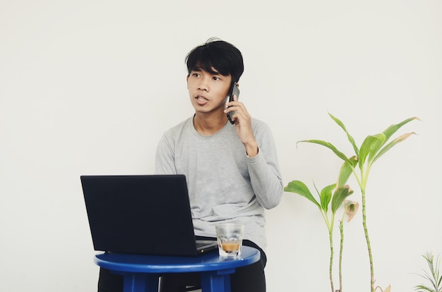 Giovane asiatico seduto davanti al laptop mentre chiama