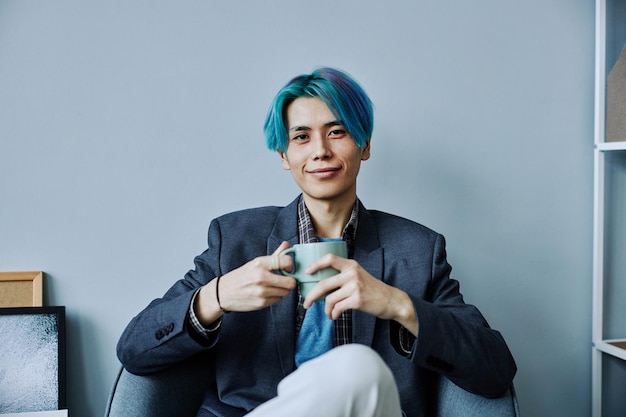 Asian young man smiling at camera and holding mug