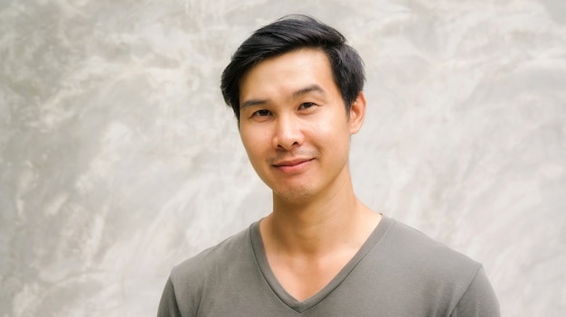 Photo asian young man smiling on a gray background.