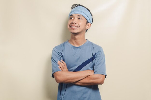 Asian young man in sports tshirt with towel on his head looking happy isolated on background