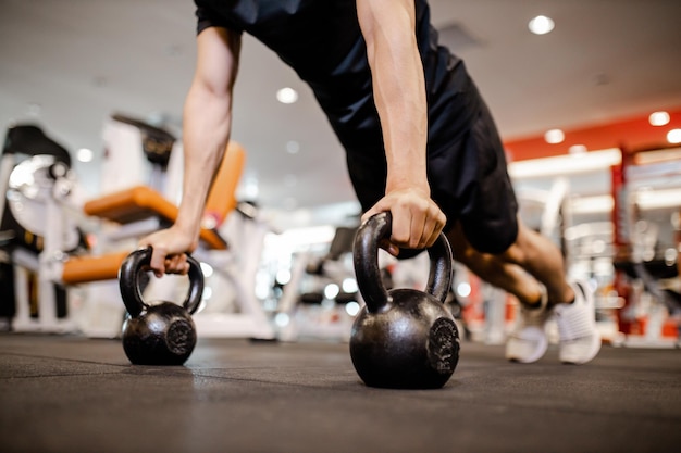 Asian young man using dumbbell pushing up exercise at gym for\
good healthy in fitness lifestyle and sport exercise concept