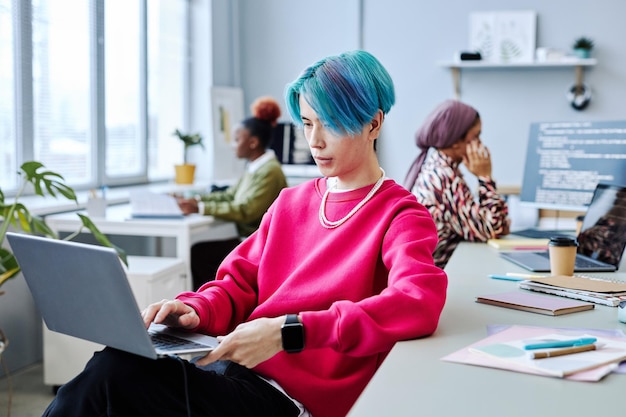 Asian young man using laptop in modern office magenta accent