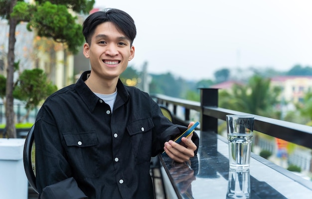 Asian young man using phone at coffee shop