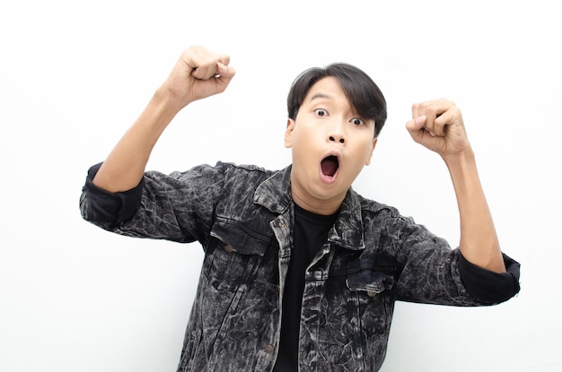 Asian young man wearing jeans jacket surprised, amazed, wow shocked raising arms yes gesture
