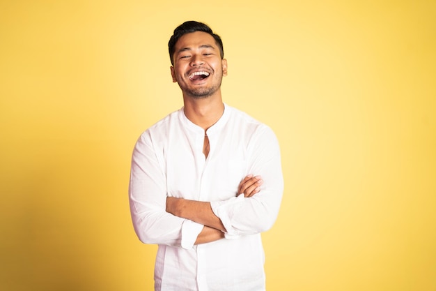 Asian young man wearing white shirt laughing with arms crossed