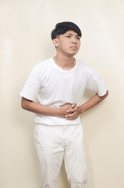 Asian young man wearing white tshirt feeling stomach ache