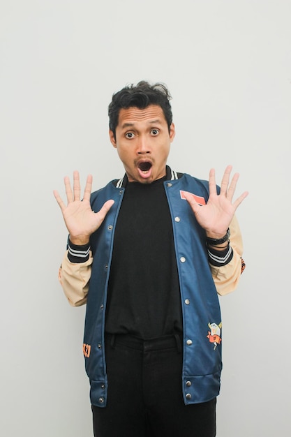 Asian young man with surprised expression facing forward over white background with copy space