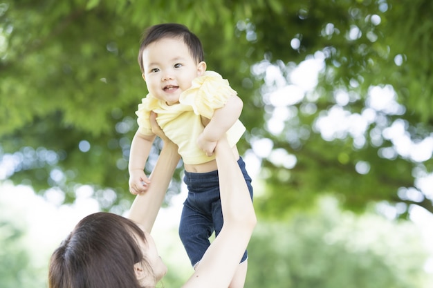 Asian young mom holding baby in green park