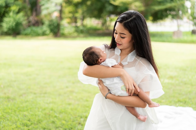 彼女の新生児を保持しているアジアの若い母親