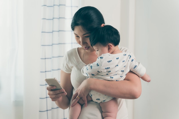 Asian young mother working and holding baby