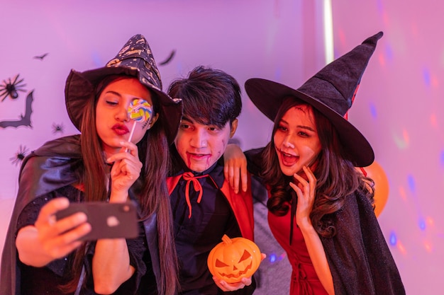 Photo asian young people in costumes celebrating halloween group having fun at party in nightclub