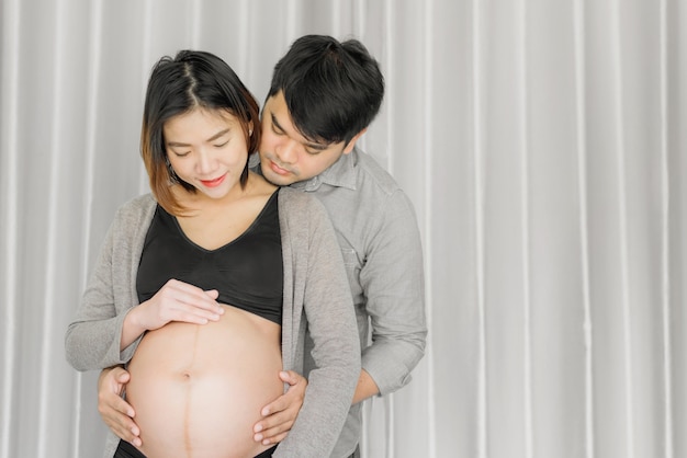 아기를 기대하는 집에서 그녀의 남편과 아시아 젊은 임신 한 여자