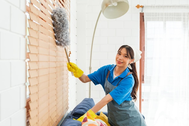 Asian young professional cleaning service woman worker working in the house Girl cleans the curtain