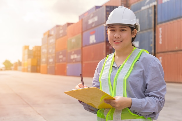 Asian young teen happy worker checking stock in shipping port work manage import export cargo containers.