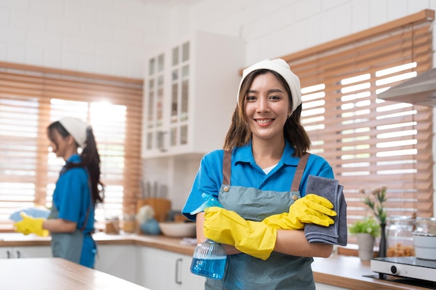 Foto braccia asiatiche della giovane donna incrociate e sorriso pronto a lavorare pulendo nella stanza della cucina