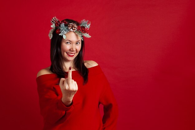 Asian young woman in a Christmas wreath showing middle finger