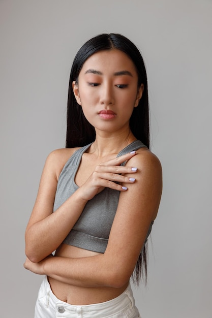 Asian young woman in crop top standing in studio