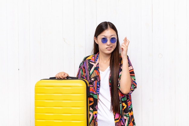 Asian young woman crossing fingers anxiously and hoping for good luck with a worried look. holidays concept