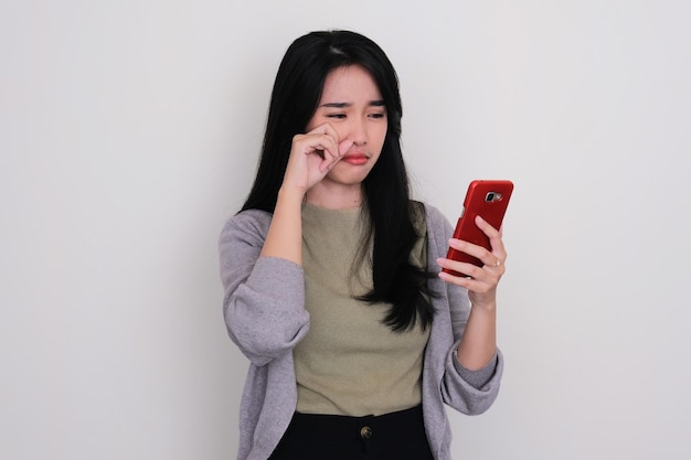 Asian young woman crying sad when looking to her mobile phone